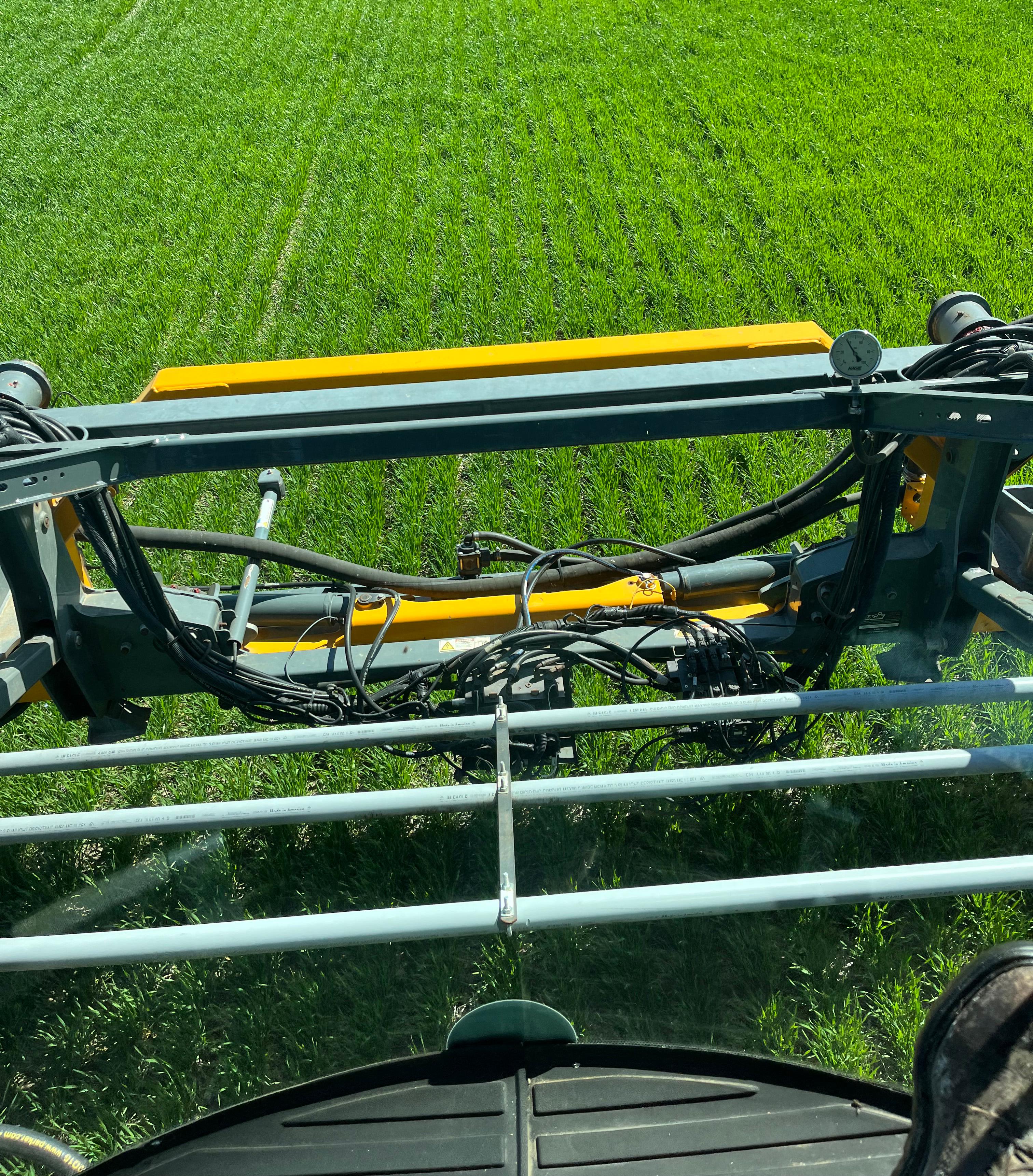 View of a wheat field from inside a tractor that is applying nitrogen to the field.